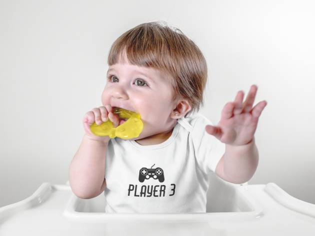 baby girl wearing a onesie while biting her toy sitting down mockup a13960