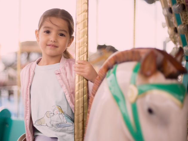 mockup of a little girl riding a carousel horse wearing a tshirt and a pink jacket 22527