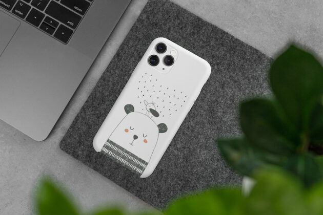 mockup of a phone case placed on a surface next to a computer 5164 el1