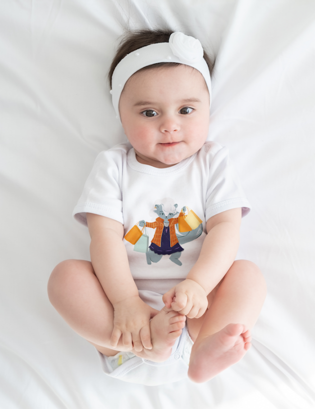 onesie mockup featuring a baby girl lying on a white bed m6223 r el2