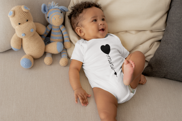 onesie mockup of a cute baby boy lying in bed with stuffed animals 25121 5