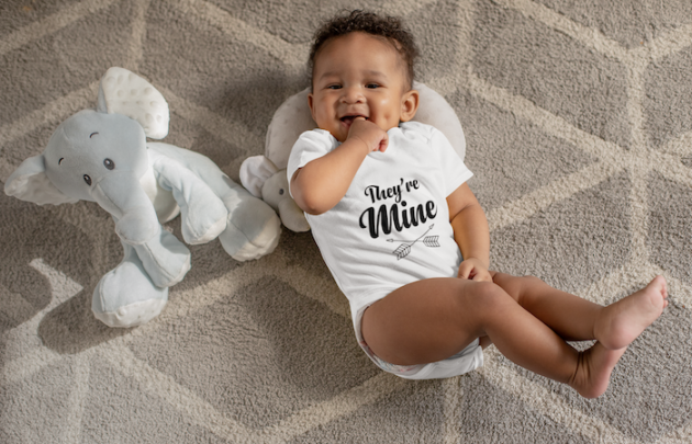 onesie mockup of a sweet baby boy with dimples next to his stuffed toys 25115 1