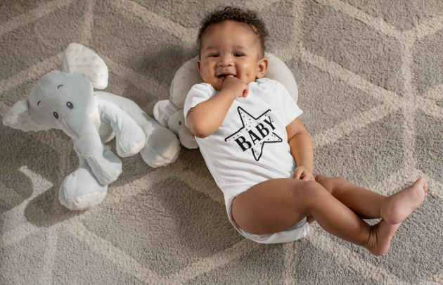 onesie mockup of a sweet baby boy with dimples next to his stuffed toys 25115 3