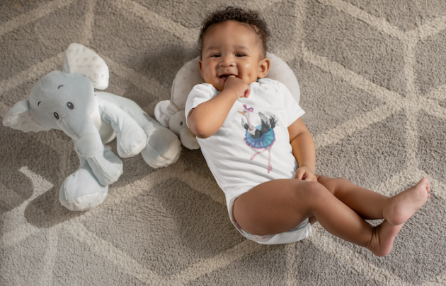 onesie mockup of a sweet baby boy with dimples next to his stuffed toys 25115 4