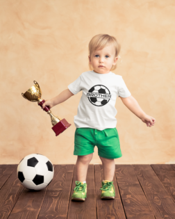 t shirt mockup of a baby boy holding a soccer trophy 43079 r el2