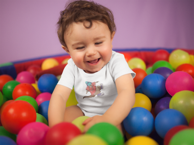 white baby boy wearing a onesie smiling while playing in the ball pit mockup 14026 2 1