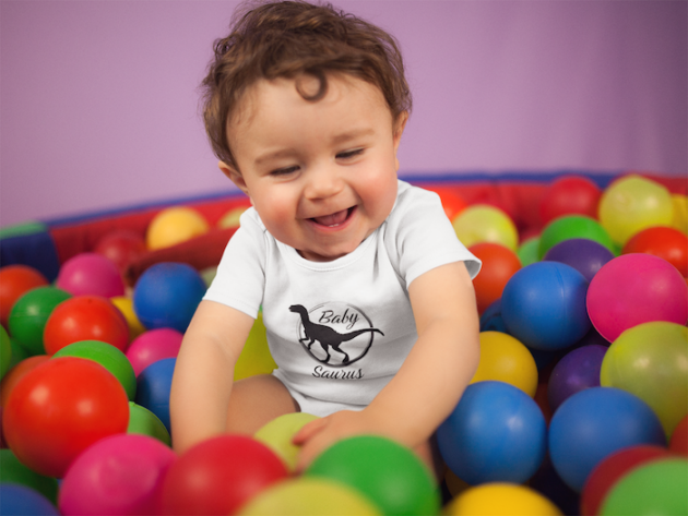 white baby boy wearing a onesie smiling while playing in the ball pit mockup 14026 3