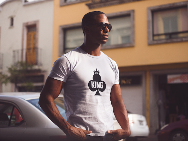 young black man wearing a short sleeved round neck t shirt and sunglasses while staring at the city mockup a14220