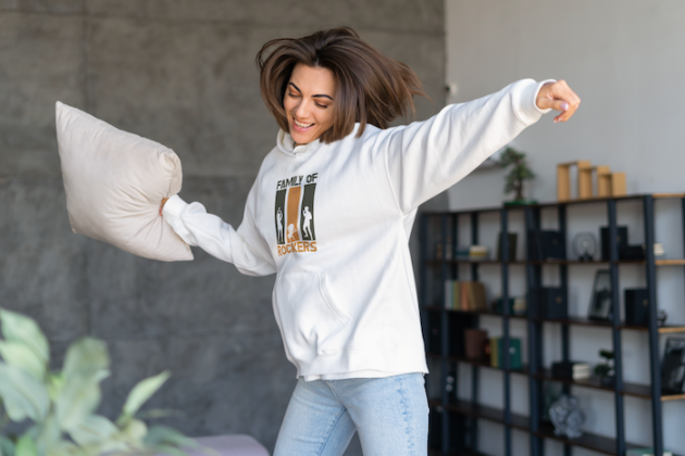 hoodie mockup featuring a smiling woman dancing at home and holding a pillow m18999 r el2