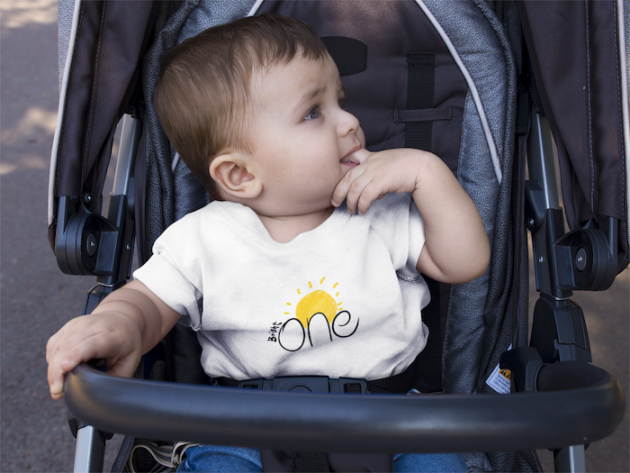 mockup of a baby boy wearing a round neck tshirt template while on his stroller a16089